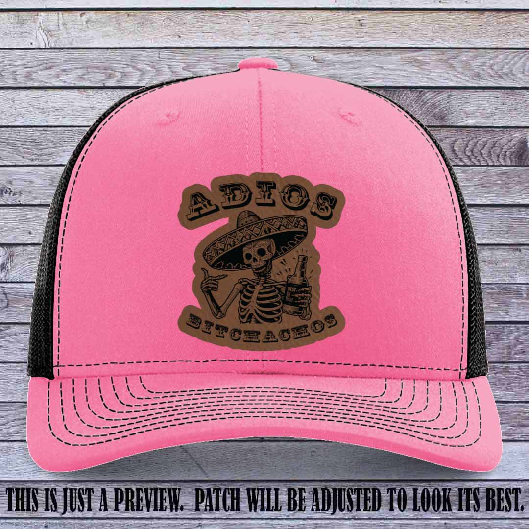 Dark brown leather patch on Hot Pink to Black Richardson 112 trucker hat featuring “Adios Bitchachos” skeleton design.