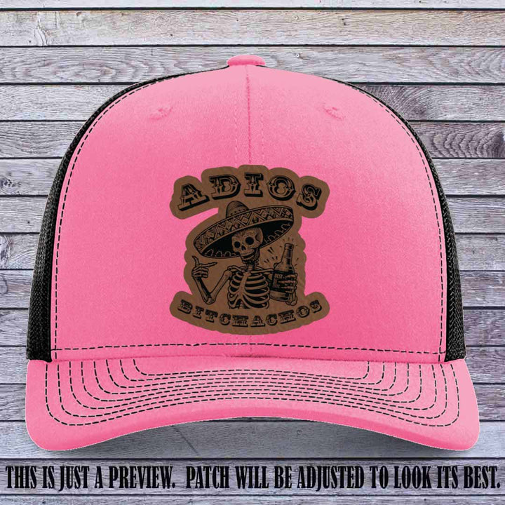 Dark brown leather patch on Hot Pink to Black Richardson 112 trucker hat featuring “Adios Bitchachos” skeleton design.
