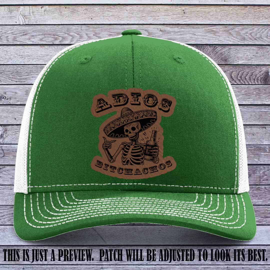 Dark brown leather patch on Kelly to White Richardson 112 trucker hat featuring “Adios Bitchachos” skeleton design.