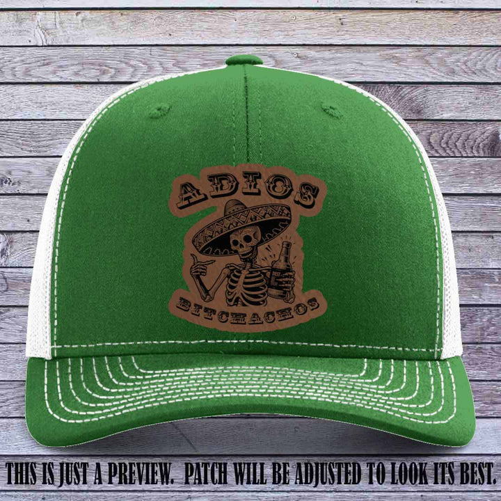 Dark brown leather patch on Kelly to White Richardson 112 trucker hat featuring “Adios Bitchachos” skeleton design.