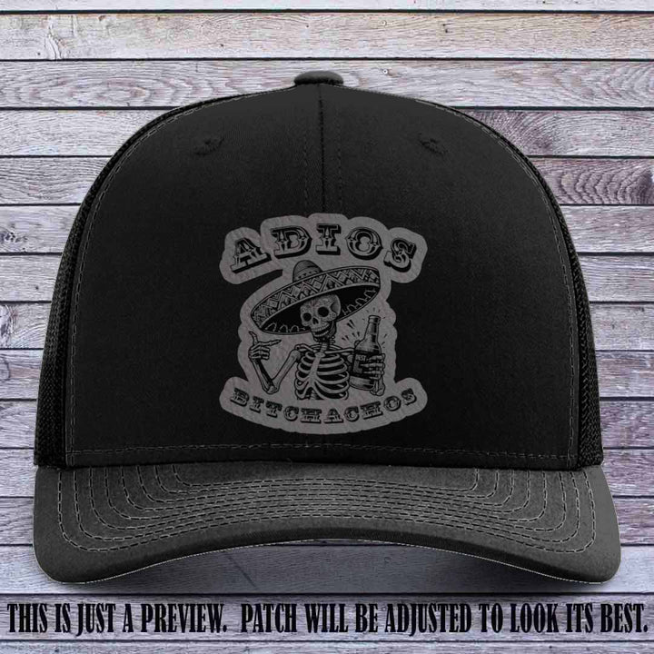 Grey leather patch on Black Richardson 112 trucker hat featuring “Adios Bitchachos” skeleton design.