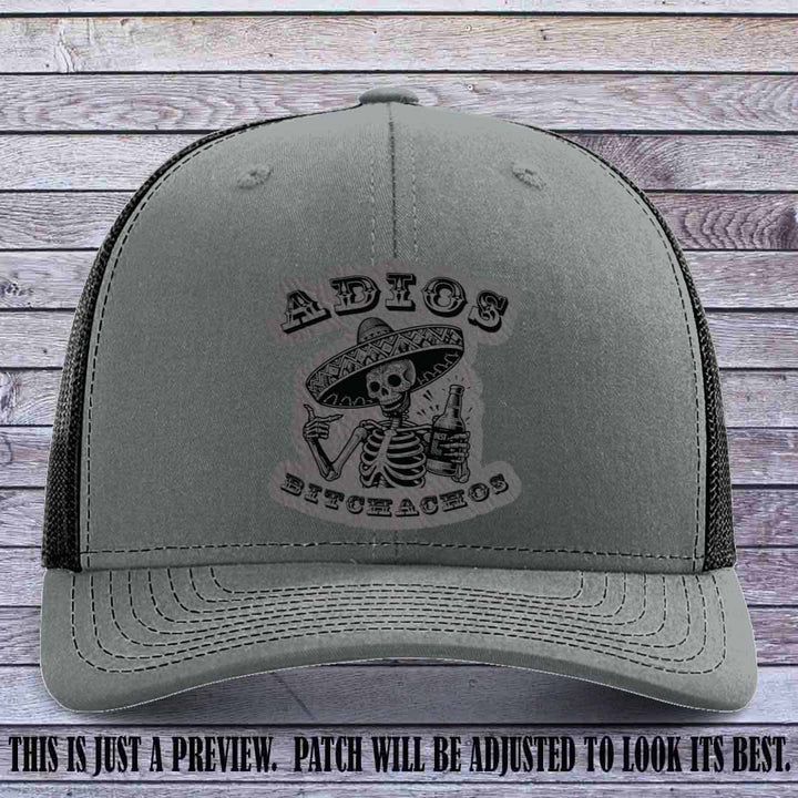 Grey leather patch on Heather Grey to Black Richardson 112 trucker hat featuring “Adios Bitchachos” skeleton design.