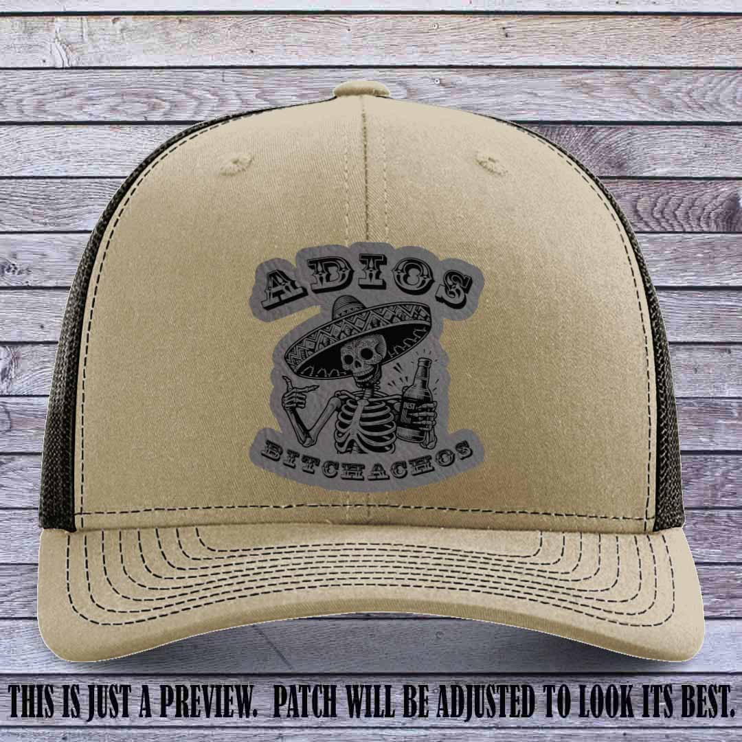 Grey leather patch on Khaki to Coffee Richardson 112 trucker hat featuring “Adios Bitchachos” skeleton design.