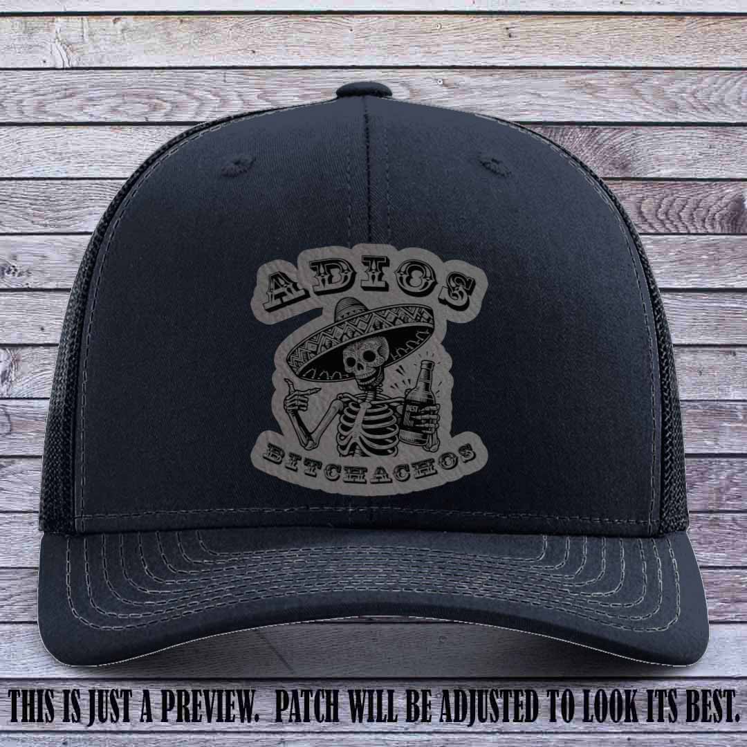Grey leather patch on Navy Richardson 112 trucker hat featuring “Adios Bitchachos” skeleton design.