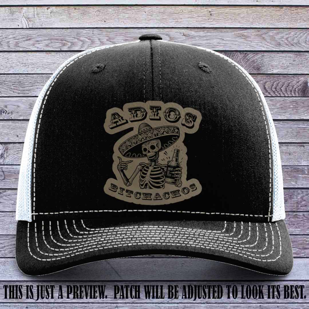Light brown leather patch on Black to White Richardson 112 trucker hat featuring “Adios Bitchachos” skeleton design.