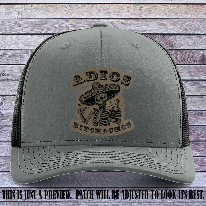Light brown leather patch on Heather Grey to Black Richardson 112 trucker hat featuring “Adios Bitchachos” skeleton design.