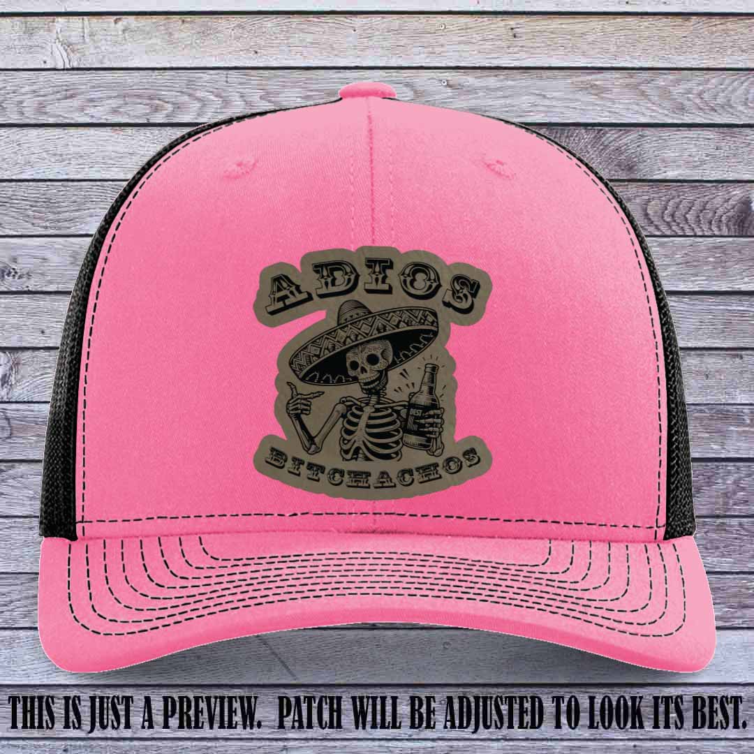 Light brown leather patch on Hot Pink to Black Richardson 112 trucker hat featuring “Adios Bitchachos” skeleton design.