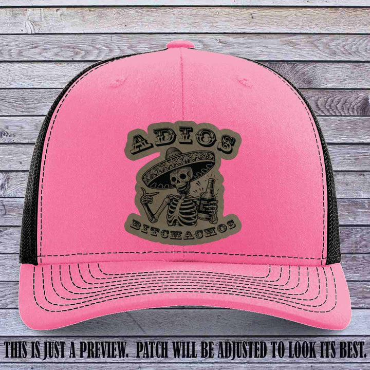 Light brown leather patch on Hot Pink to Black Richardson 112 trucker hat featuring “Adios Bitchachos” skeleton design.