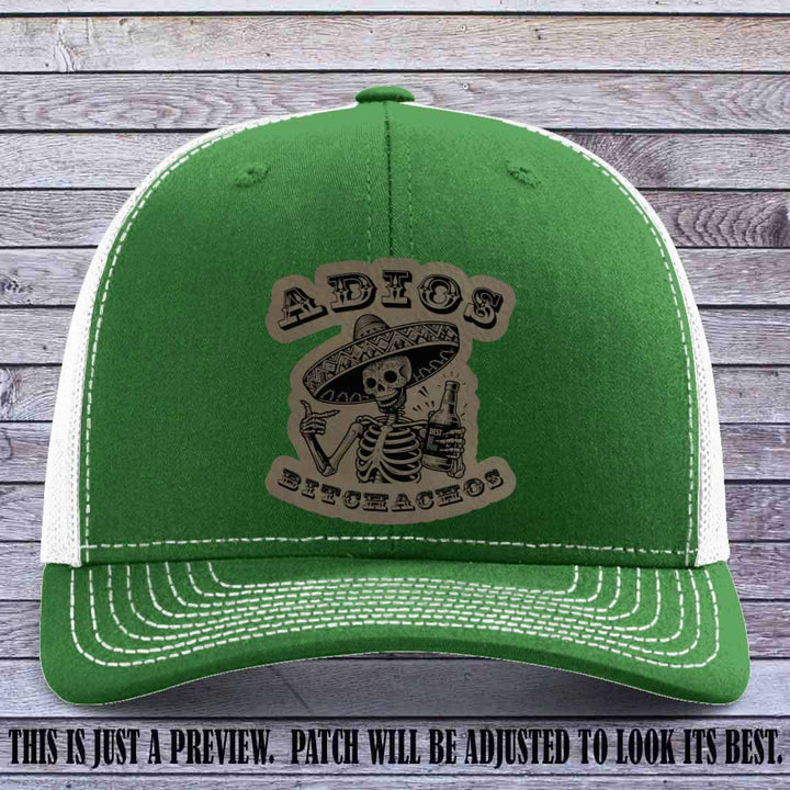 Light brown leather patch on Kelly to White Richardson 112 trucker hat featuring “Adios Bitchachos” skeleton design.