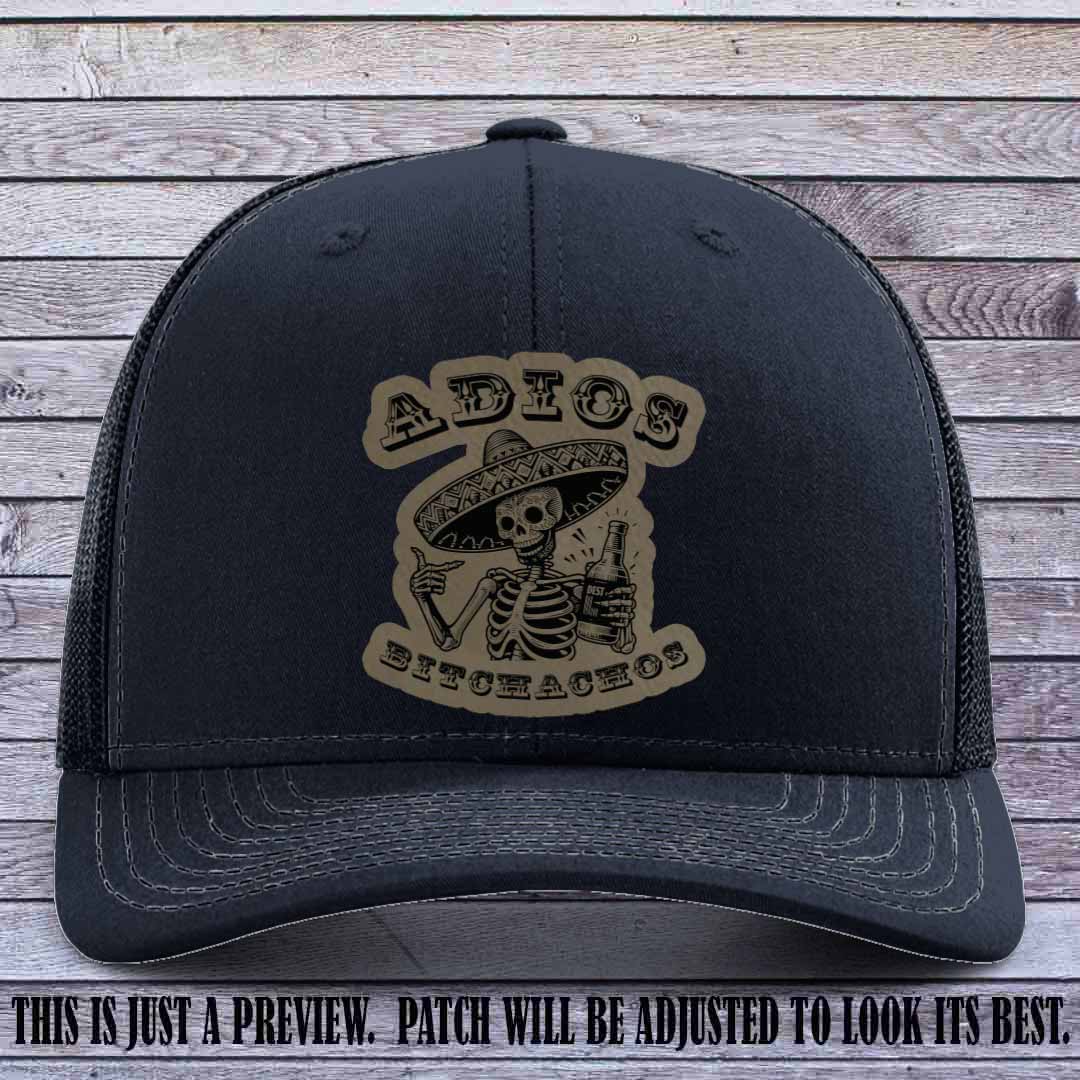 Light brown leather patch on Navy Richardson 112 trucker hat featuring “Adios Bitchachos” skeleton design.