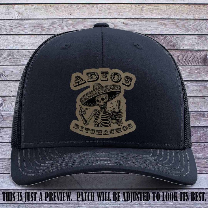 Light brown leather patch on Navy Richardson 112 trucker hat featuring “Adios Bitchachos” skeleton design.