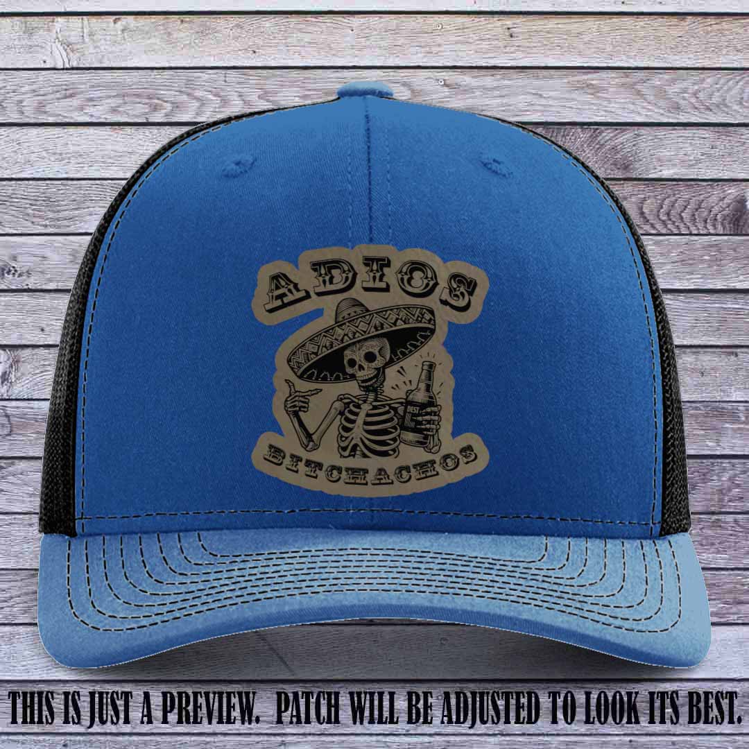 Light brown leather patch on Royal to Black Richardson 112 trucker hat featuring “Adios Bitchachos” skeleton design.