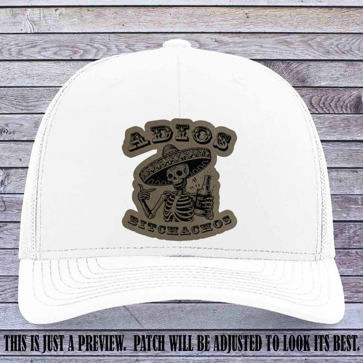 Light brown leather patch on White Richardson 112 trucker hat featuring “Adios Bitchachos” skeleton design.