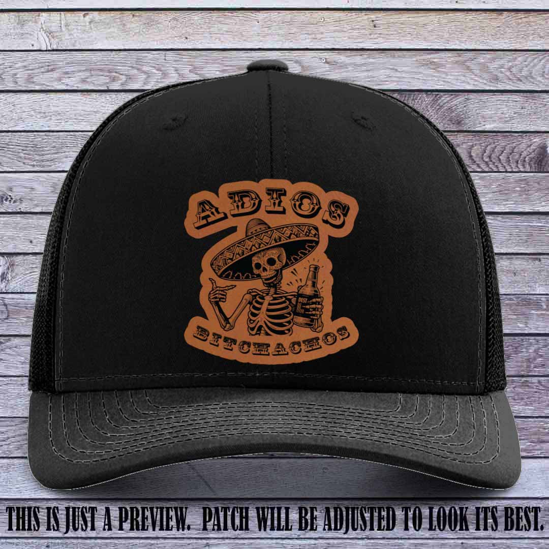 Rawhide leather patch on Black Richardson 112 trucker hat featuring “Adios Bitchachos” skeleton design.