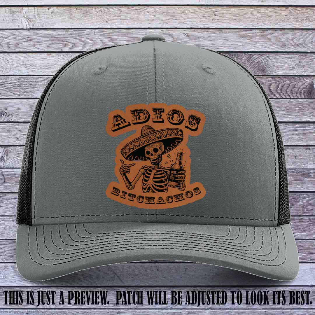 Rawhide leather patch on Heather Grey to Black Richardson 112 trucker hat featuring “Adios Bitchachos” skeleton design.