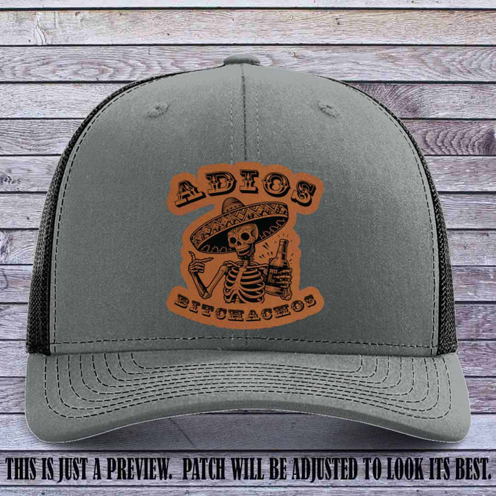 Rawhide leather patch on Heather Grey to Black Richardson 112 trucker hat featuring “Adios Bitchachos” skeleton design.