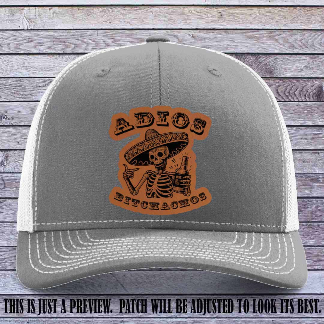 Rawhide leather patch on Heather Grey to White Richardson 112 trucker hat featuring “Adios Bitchachos” skeleton design.