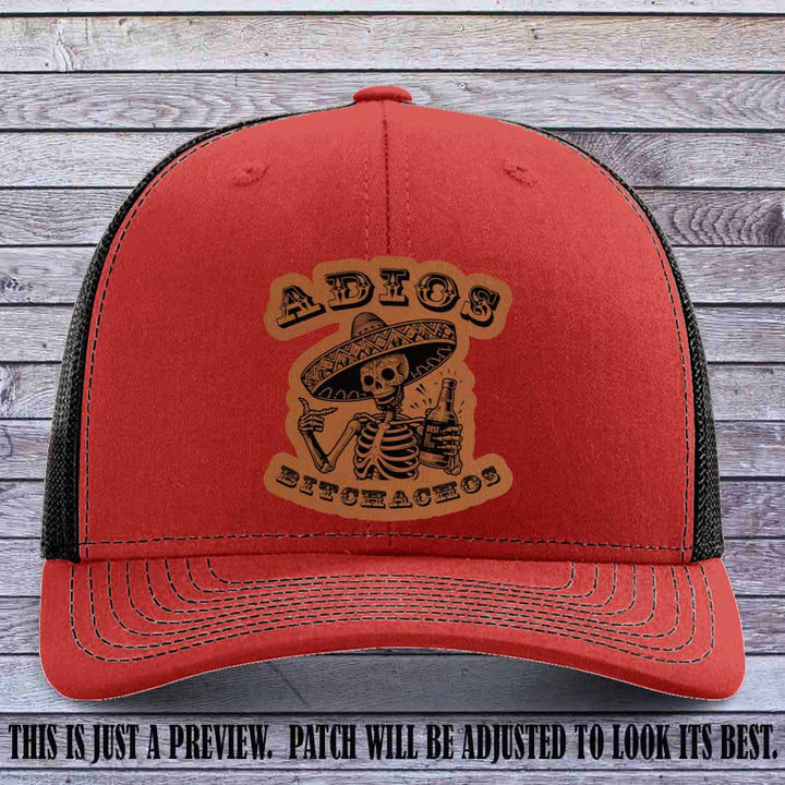 Rawhide leather patch on Red to Black Richardson 112 trucker hat featuring “Adios Bitchachos” skeleton design.